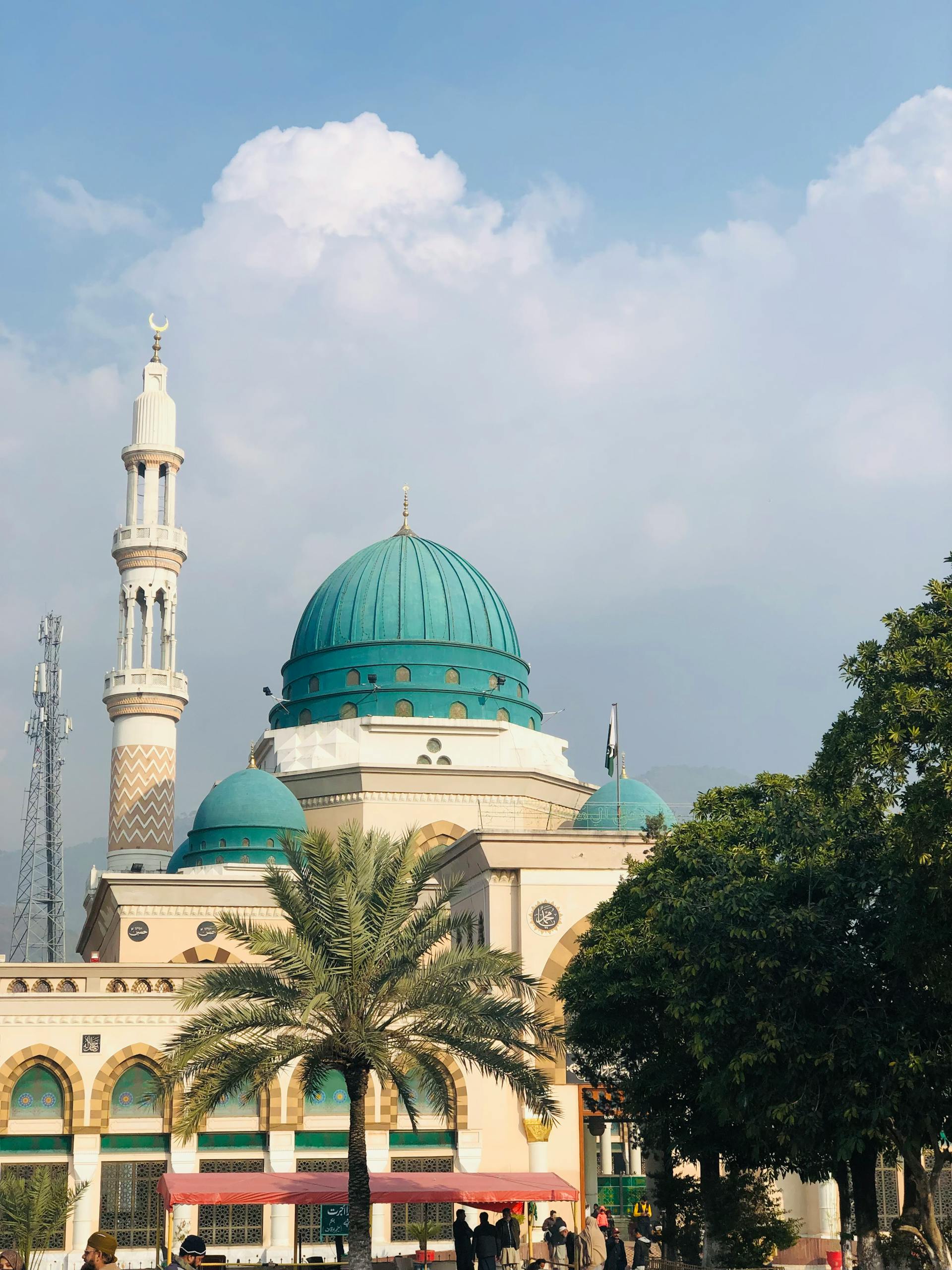 Beautiful mosque with a distinctive blue dome and minaret under a clear sky.